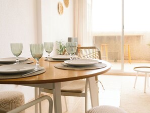 A dining table set with plates, glasses, and a chair. - Terraza Azul - Penthouse with sea view by Interhome (Alcocéber/Alcossebre)