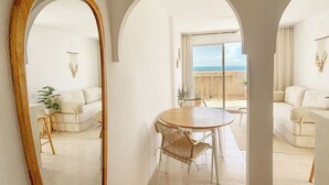 A room with a dining area, white furniture, a large mirror, and a view of the sea. - Terraza Azul - Penthouse with sea view by Interhome (Alcocéber/Alcossebre)