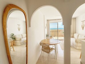 Ein Zimmer mit Essbereich, weißen Möbeln, einem großen Spiegel und Meerblick.