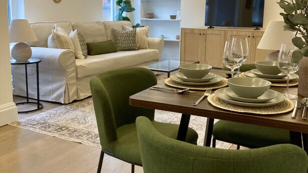 Una sala de estar moderna con comedor, que incluye un conjunto de sofá, una mesa de centro y un televisor al fondo.