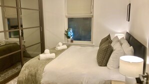 Un dormitorio ordenado con cama, lámpara de noche y ventana con vistas.