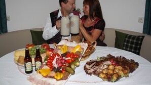 A dining table with a variety of foods and drinks, including cheese, meats, fruits, and bottles. - Cozy vacation home in charming nature and mountain scenery! Dogs welcome! (Abtenau)