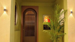 A staircase leading to a door with a barred window, a potted plant, and a sign indicating a palace. - Bun And Bunks Udaipur (Udaipur)