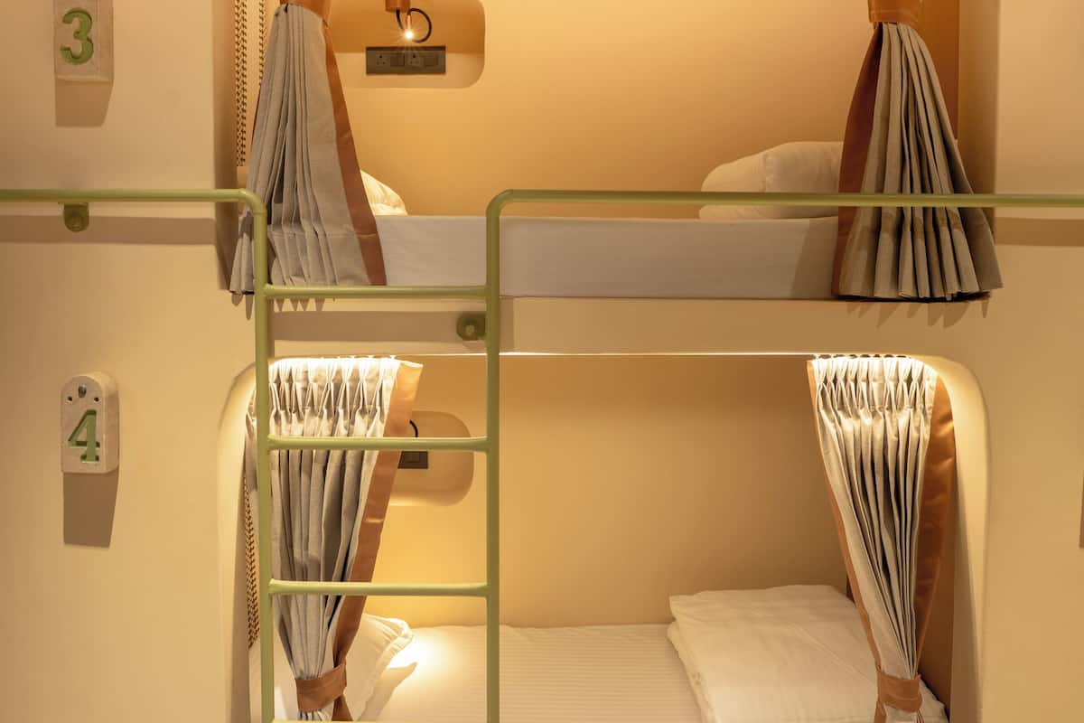 A bunk bed room with curtains, a wall-mounted light, and a number indicating the room.