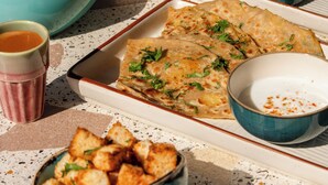 A table with various dishes, including flatbreads, a bowl of rice, and a cup of tea. - Bun And Bunks Udaipur (Udaipur)