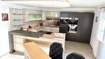 A modern kitchen with a central island, dark cabinets, and a dining area with two chairs.