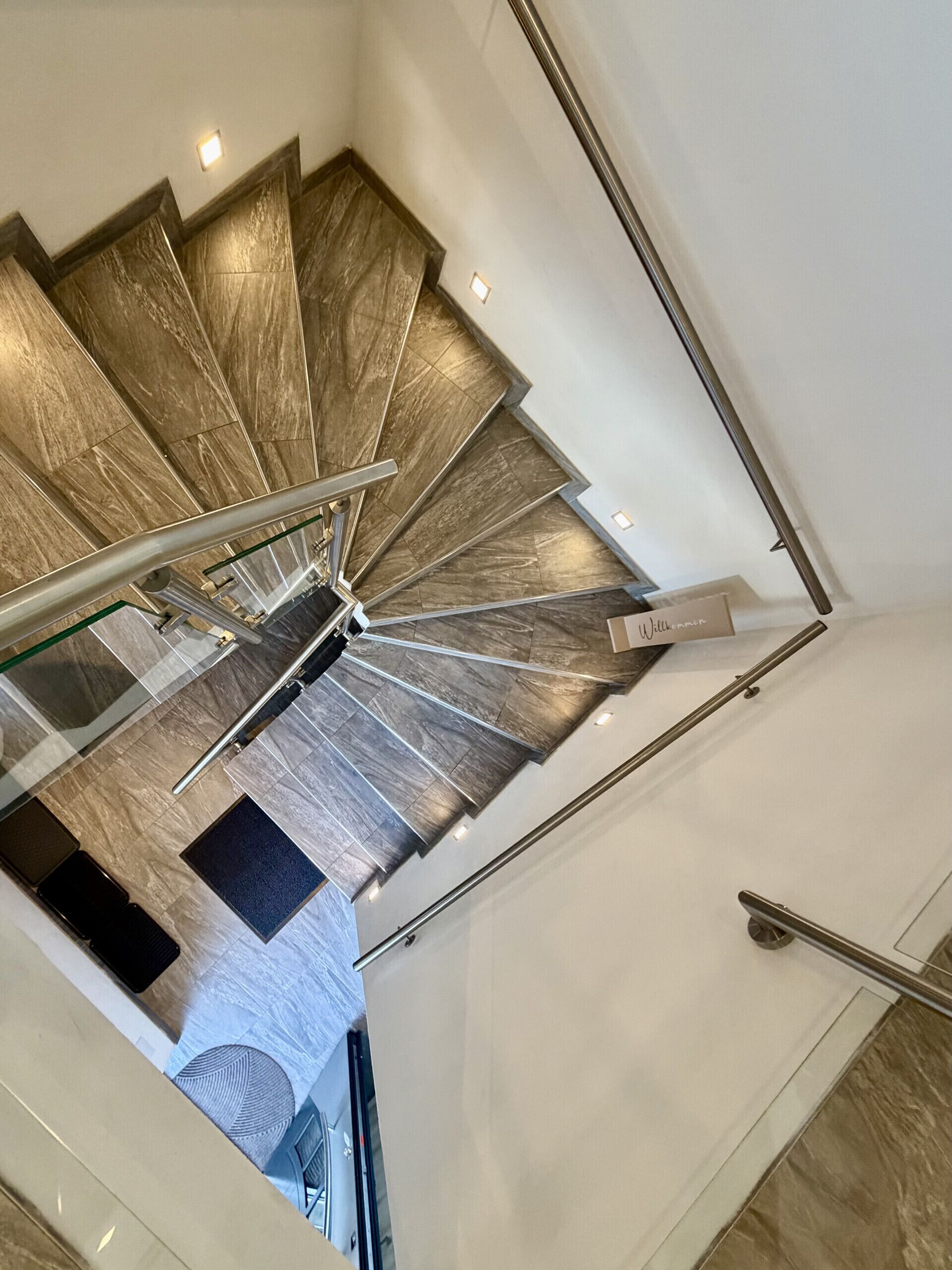 Un escalier en colimaçon avec une rampe et une main courante en métal, menant à l’étage supérieur.