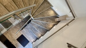 Escada em espiral com guarda-corpo e corrimão, que leva a um andar superior.