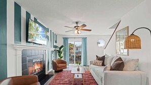 Ein Wohnzimmer mit Kamin, Deckenventilator, einem weißen Sofa und einem roten Teppich.