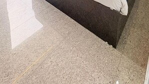Habitació d'hotel moderna amb un llit gran, un ventilador de sostre i vista a la ciutat a través d'una finestra ampla.
