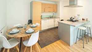 Una cocina moderna con armarios de madera, una isla central con taburetes y una zona de comedor con una mesa redonda y sillas.