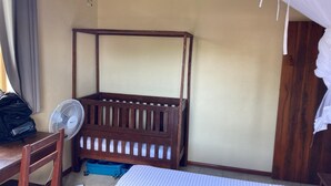 A room with a wooden four-poster bed, a small table with a fan, and a blue storage box. - CASA DENISE ILE SAINTE MARIE VOHILAVA MADA New fully-equipped house with garden (sainte marie - ambodifotatra)