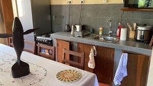 A kitchen with a gas stove, a coffee maker, a kettle, a sink, and cabinets. - CASA DENISE ILE SAINTE MARIE VOHILAVA MADA New fully-equipped house with garden (sainte marie - ambodifotatra)