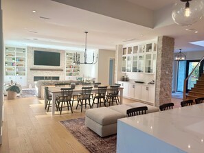 Une cuisine moderne avec des meubles blancs, un îlot central et un coin repas comprenant des chaises et une table.