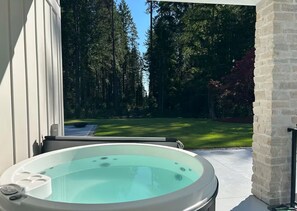 Un jacuzzi con vistas despejadas a un área boscosa y un césped cuidado.
