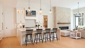 A modern kitchen with a central island, bar stools, and pendant lighting. - FIFA World Cup. Brand new 6 BD, 8 BA, Whiskey Room, Games room+ more (West Vancouver)