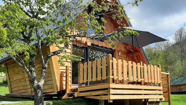 A wooden cabin with a porch and a large umbrella.