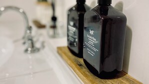 Ein Badezimmer mit einem hölzernen Regal, auf dem zwei Hautpflegeprodukte stehen.