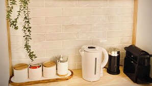 Eine Küchenarbeitsplatte mit Kaffeemaschine, Wasserkocher und Kaffeemühle. Auf der Arbeitsplatte stehen Gläser mit den Aufschriften 'Tee' und 'Kaffee'.