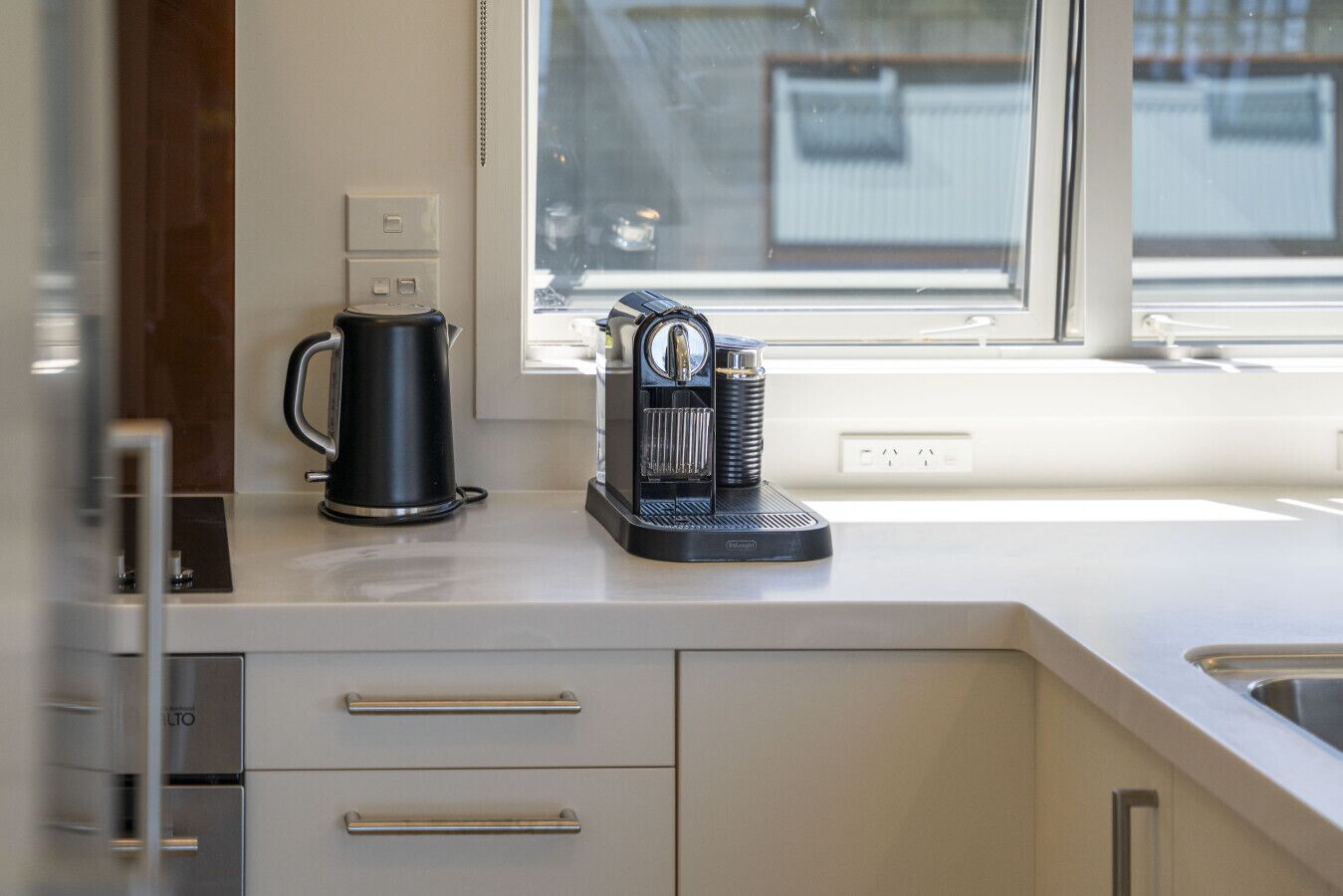 Una cocina moderna con cafetera, hervidor y molinillo de café sobre la encimera.