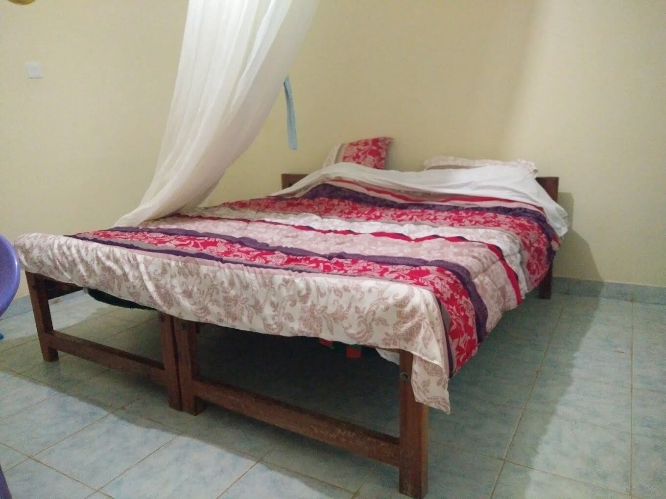 Una cama individual con dosel, estructura de madera y edredón estampado.