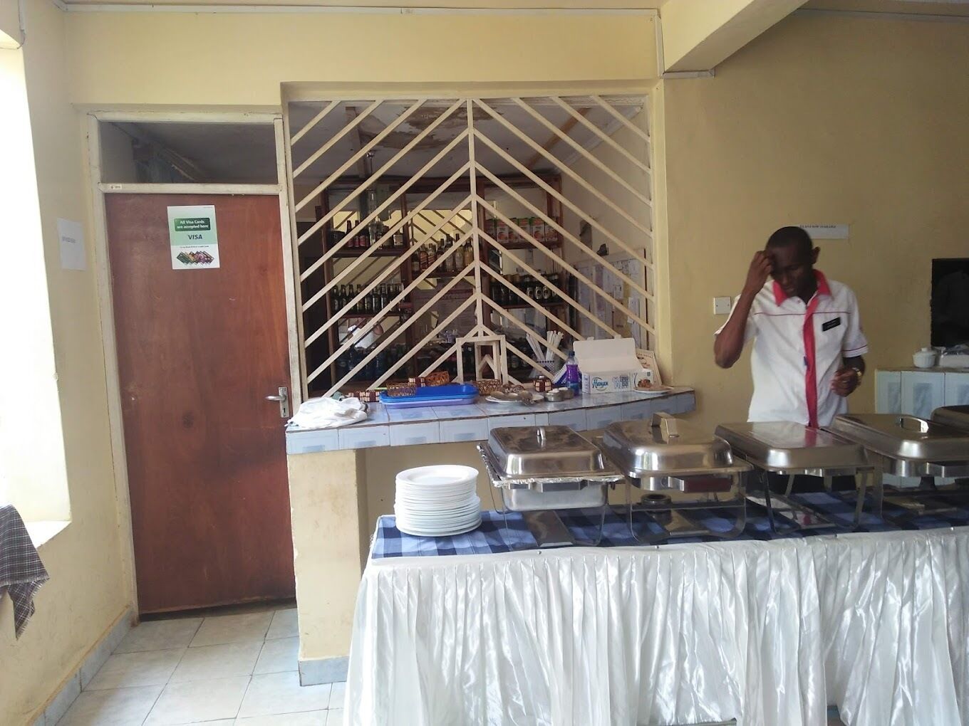 A buffet setup with a counter, food containers, and a person standing behind it.
