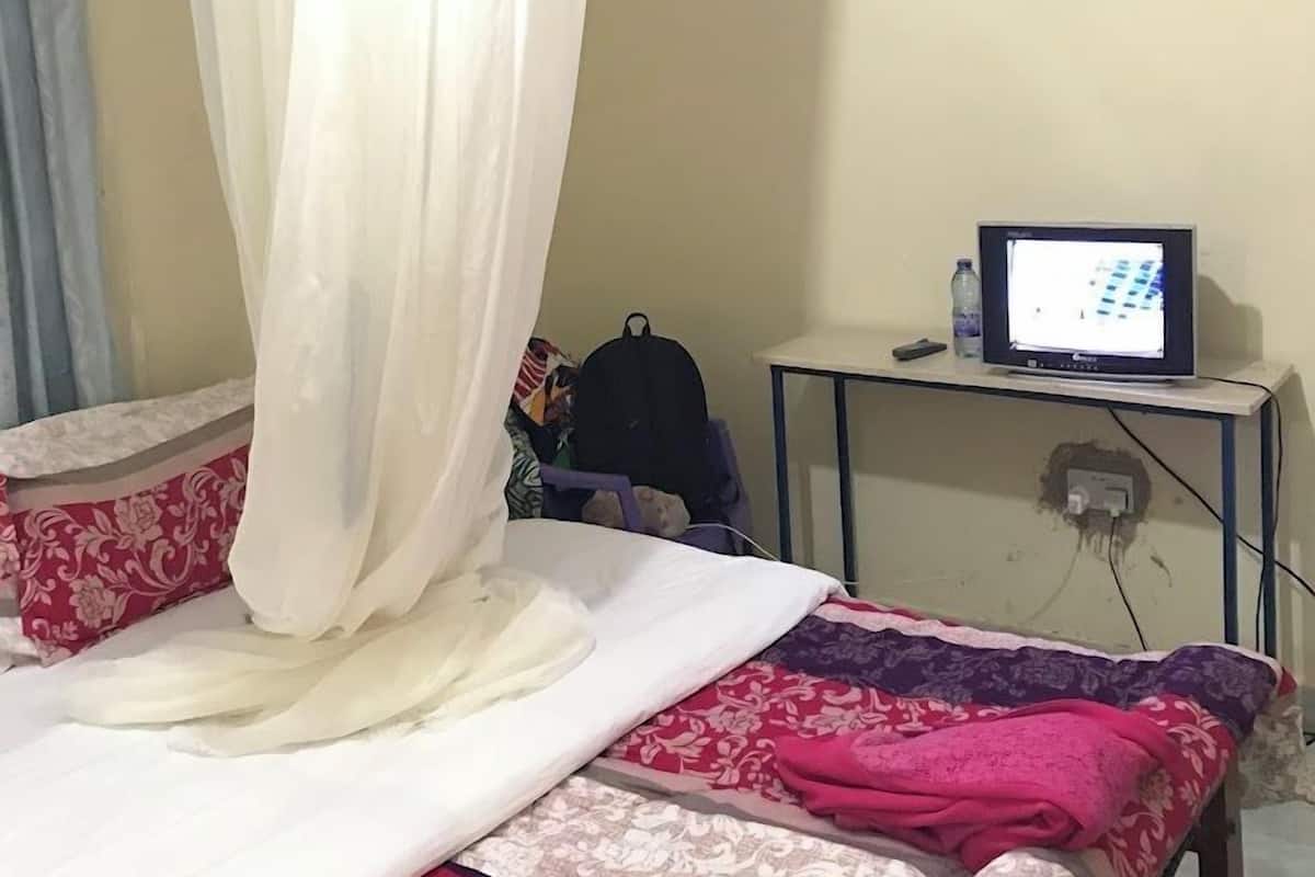 Ein Schlafzimmer mit einem Himmelsbett, einem Fernseher auf einem kleinen Tisch und einem Rucksack auf dem Boden.
