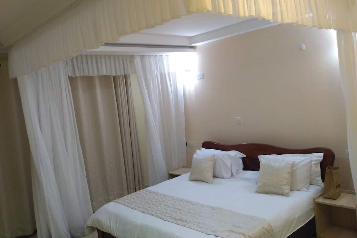 Ein Schlafzimmer mit einem Bett, weißen Vorhängen und einem Fenster.