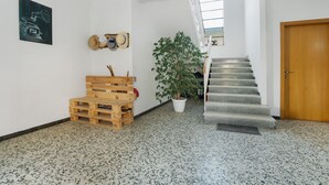Ein Flur mit einer Holzbänkl, einem Blumentopf, einer Treppe und einer Tür.