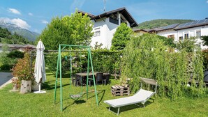 Ein Garten mit Schaukel, Liegestuhl und Essbereich mit Gartenmöbeln.