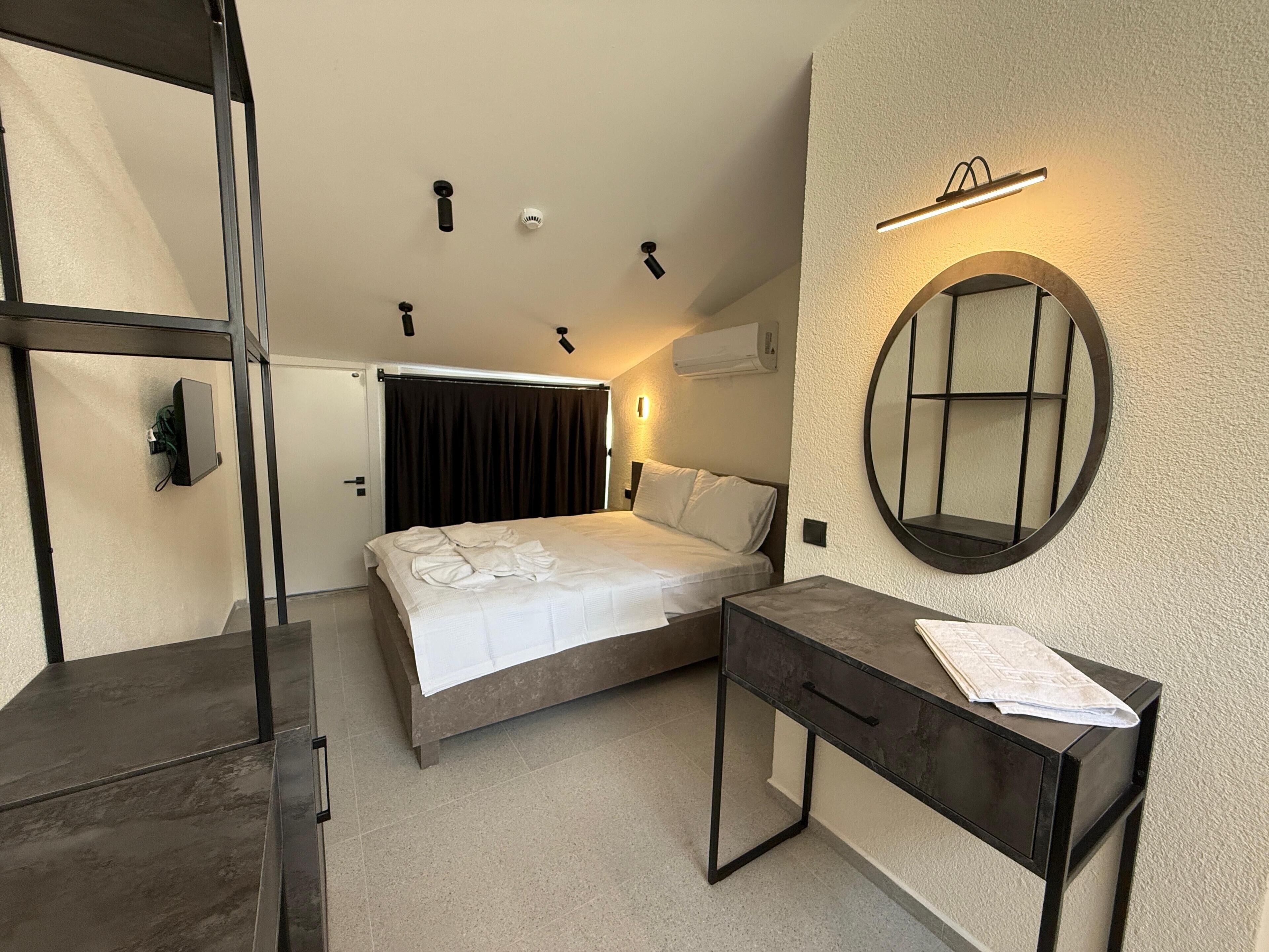 A bedroom with a bed, bedside table, and a mirror on the wall.