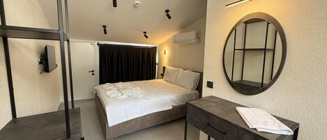 A bedroom with a bed, bedside table, and a mirror on the wall.