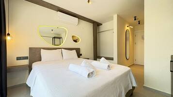 Una habitación de hotel con una cama grande, un espejo y un aire acondicionado de pared.