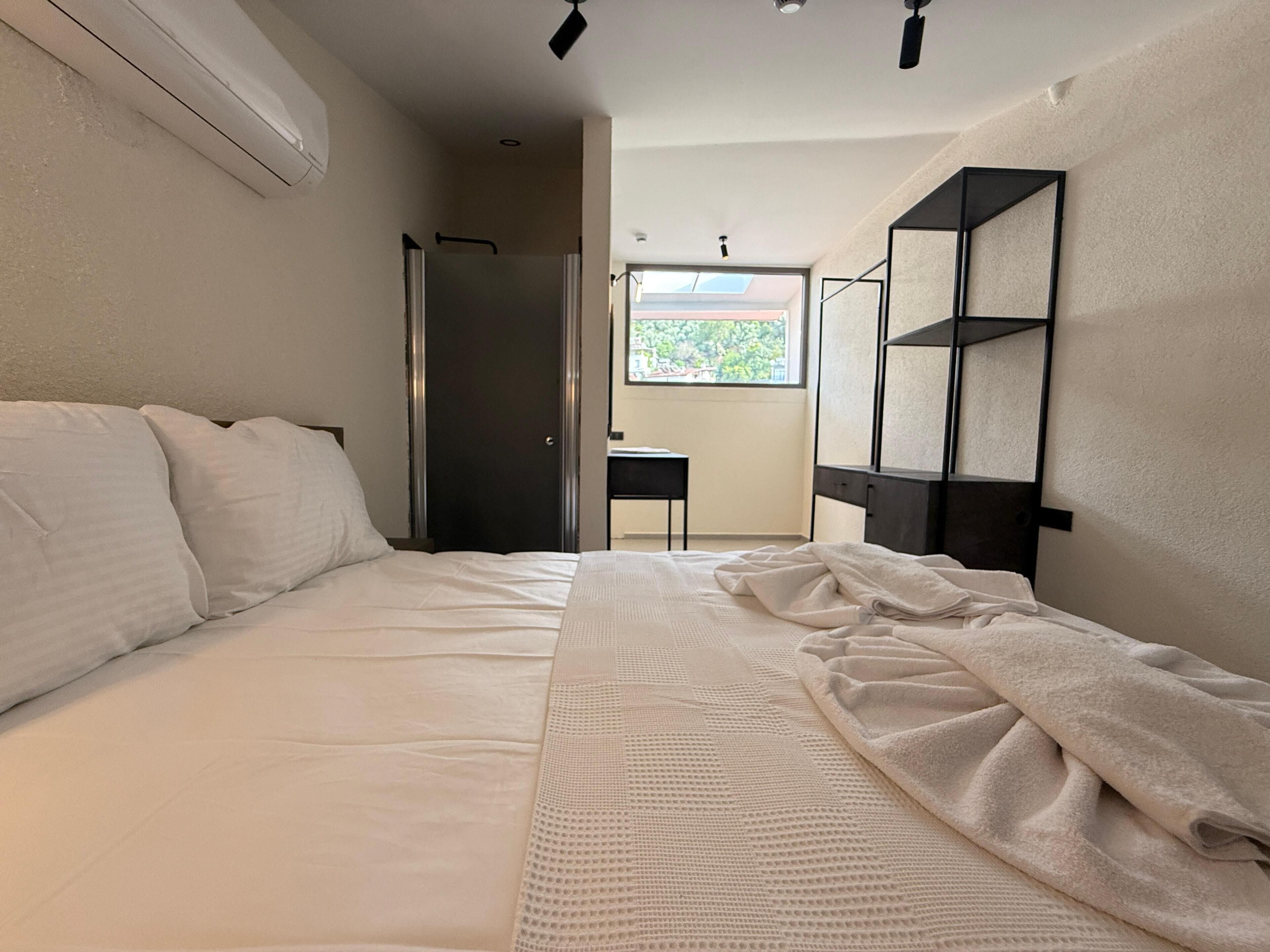 Un dormitorio con cama, escritorio y ventana con vistas a zonas verdes.