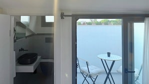 Un balcon avec une table et des chaises, une vue sur une étendue d’eau, et un coin cuisine équipé d’un évier et d’une cuisinière.