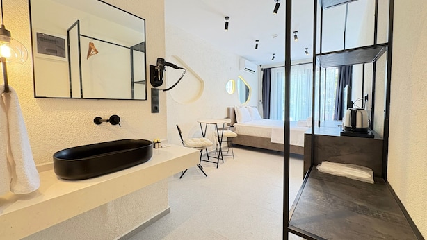 Une salle de bain moderne avec un grand miroir, un lavabo noir et un sèche-cheveux.