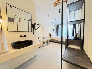 Un baño moderno con un espejo grande, un lavabo negro y un secador de pelo.