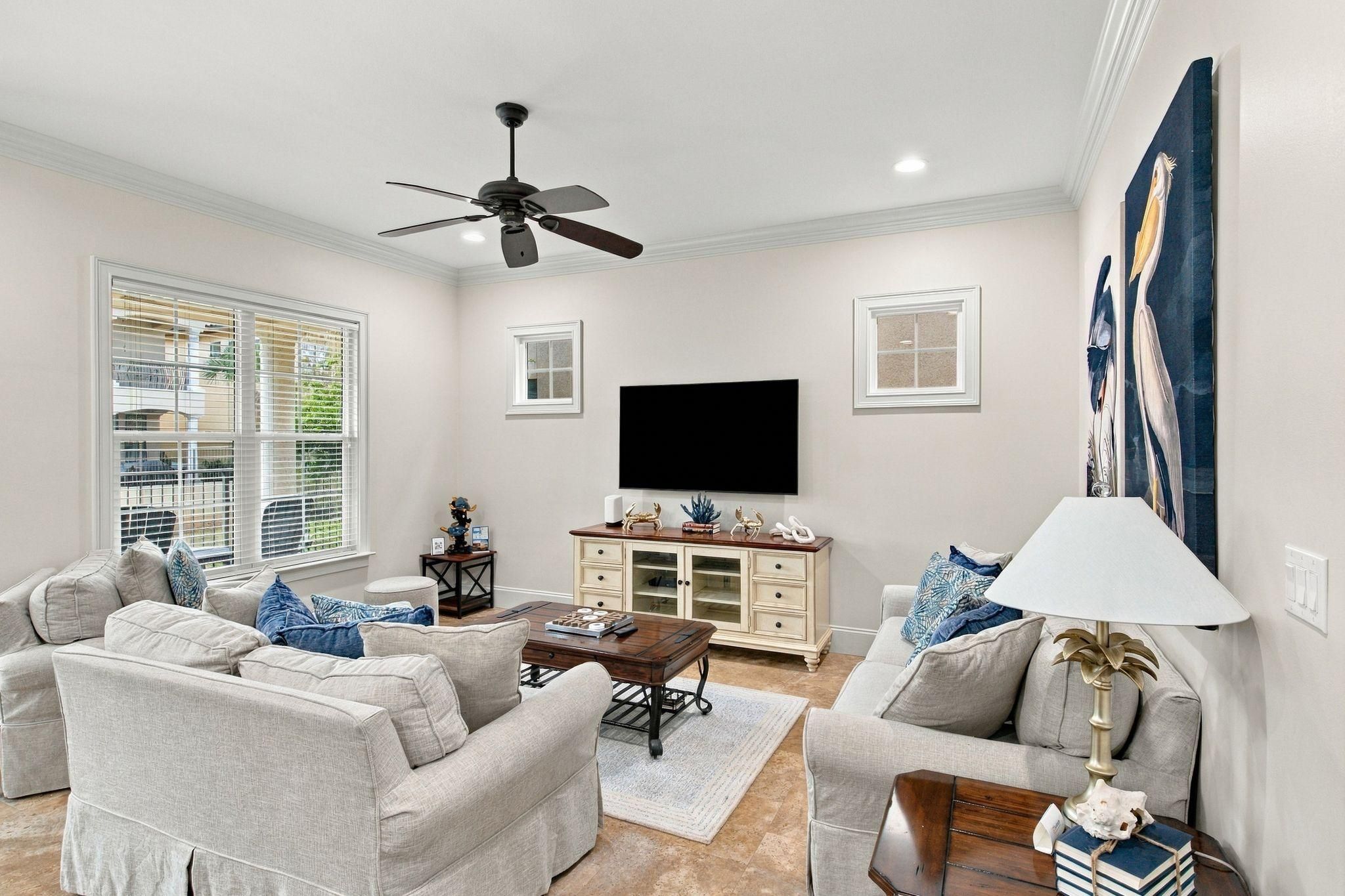 A living room with a ceiling fan, a flat-screen TV, a coffee table, and a sofa set.