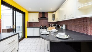 Een moderne keuken met witte kasten, een zwart aanrecht en een rode betegelde muur.