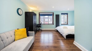 Een slaapkamer met een bed, een bank, een bureau en een stoel.