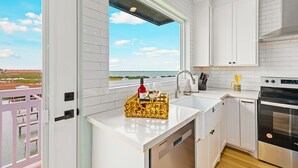 Una cocina moderna con armarios blancos, un horno de acero inoxidable y un ventanal con vistas panorámicas.