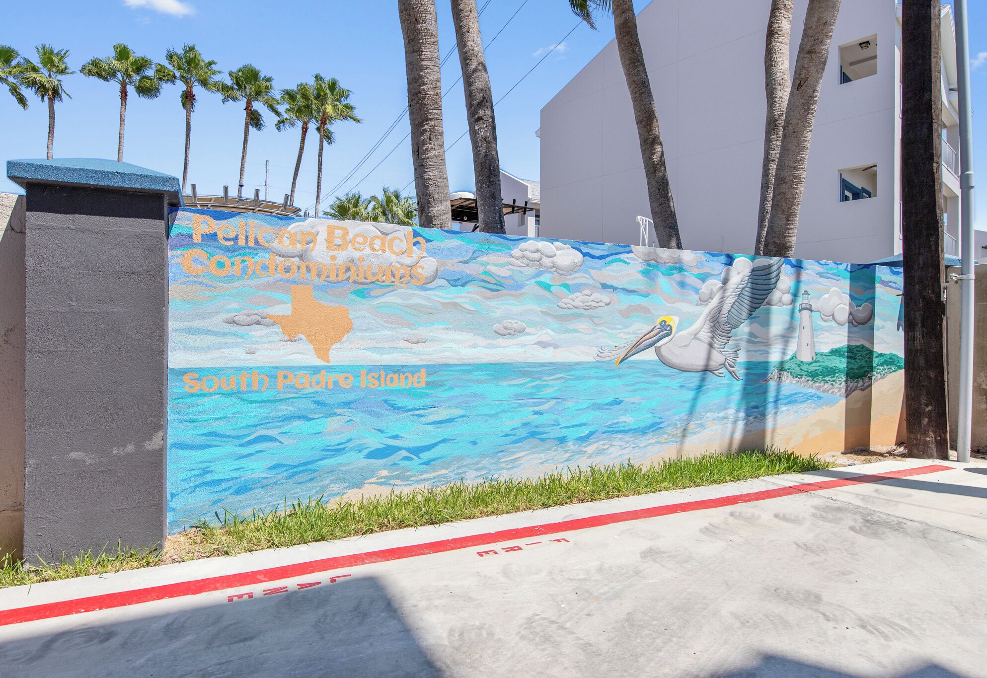 A mural of a beach scene with a pelican and lighthouse, and text indicating 'Pelican Beach Condominiums South Padre Island'.