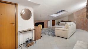 A spacious living area with a sofa, a coffee table, a TV, and a fireplace.
