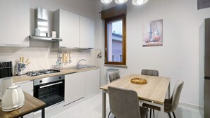 A modern kitchen with white cabinets, a wooden dining table, and a window with a view.