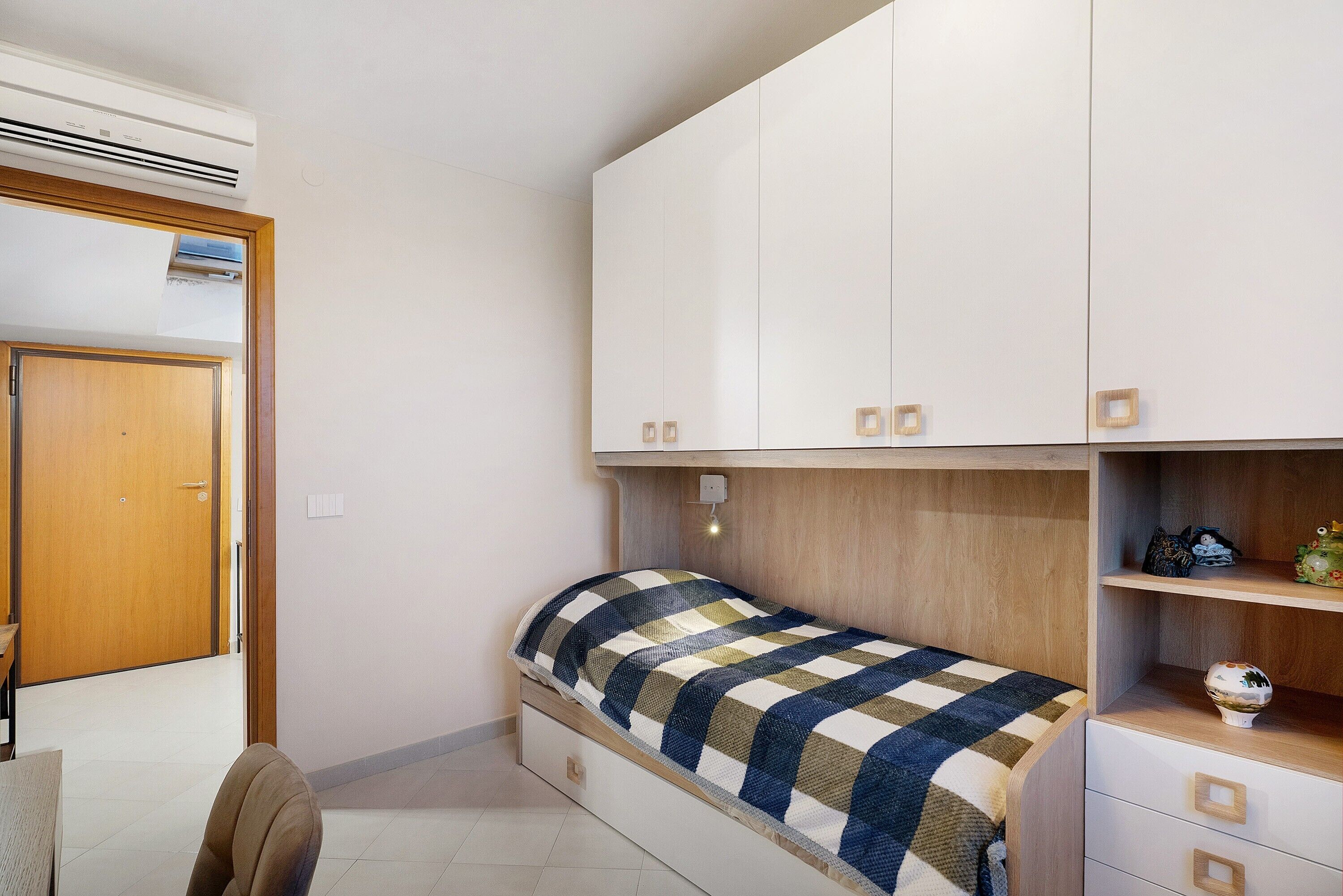 Une chambre à coucher comprenant un lit, une armoire, un bureau et un appareil de climatisation.