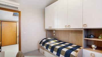 Une chambre à coucher comprenant un lit, une armoire, un bureau et un appareil de climatisation.