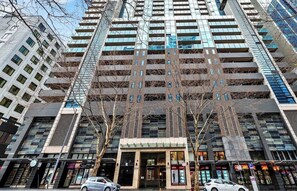 A multi-story building with a central entrance, large windows, and a modern architectural design. - Shared Apartment-Private bedroom/bathroom in Melbourne CBD (West Melbourne)