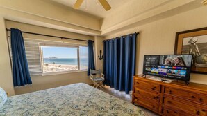 Ein Schlafzimmer mit Bett, Schminktisch, Fernseher und Blick auf den Strand.