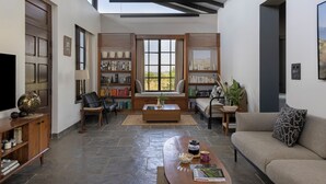 Un salon spacieux doté d’un haut plafond, de bibliothèques intégrées, d’un canapé confortable et d’une grande fenêtre offrant une vue sur l’extérieur.