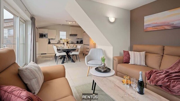 Ein modernes Wohnzimmer mit einer Couch, einem Couchtisch und einem Essbereich im Hintergrund.